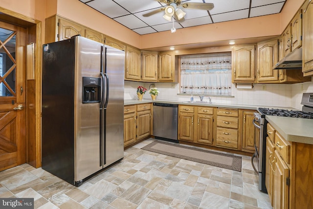 kitchen with ceiling fan, sink, a drop ceiling, decorative backsplash, and appliances with stainless steel finishes