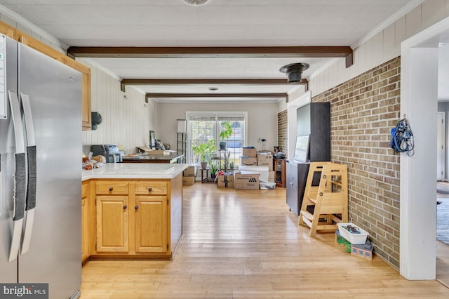 kitchen with stainless steel fridge, ornamental molding, beam ceiling, kitchen peninsula, and light hardwood / wood-style floors