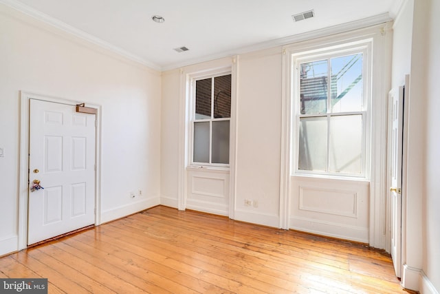 spare room featuring light wood-type flooring and crown molding