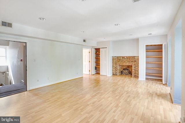 unfurnished living room with light hardwood / wood-style floors and a brick fireplace