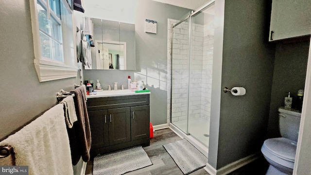 bathroom featuring hardwood / wood-style flooring, a shower with door, vanity, and toilet