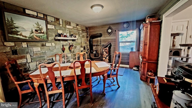 dining room featuring a wood stove, hardwood / wood-style floors, and wooden walls