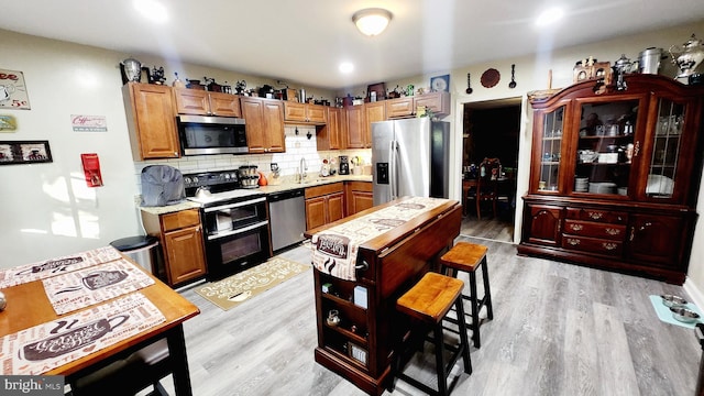 kitchen with stainless steel appliances, tasteful backsplash, light wood-type flooring, and sink