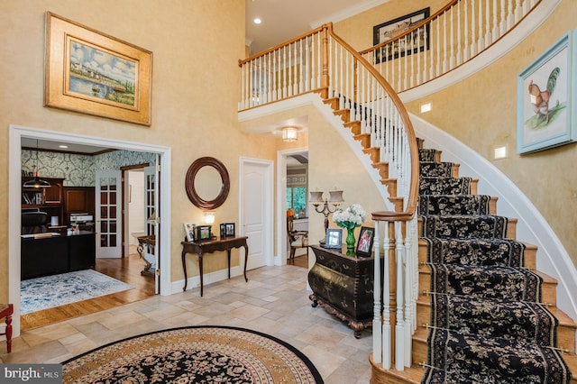 entrance foyer with ornamental molding, light hardwood / wood-style floors, and a towering ceiling