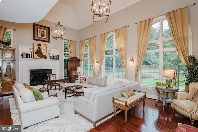 living room featuring a premium fireplace, lofted ceiling, hardwood / wood-style floors, and a chandelier