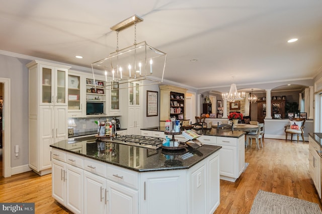 kitchen featuring a center island, white cabinetry, light hardwood / wood-style floors, pendant lighting, and ornamental molding