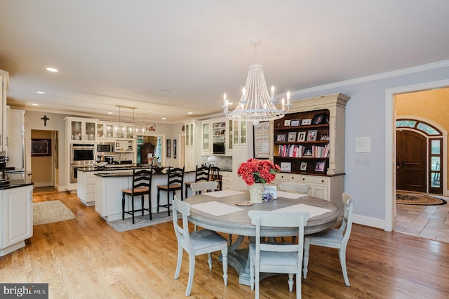 dining area featuring light hardwood / wood-style floors, ornamental molding, and a chandelier