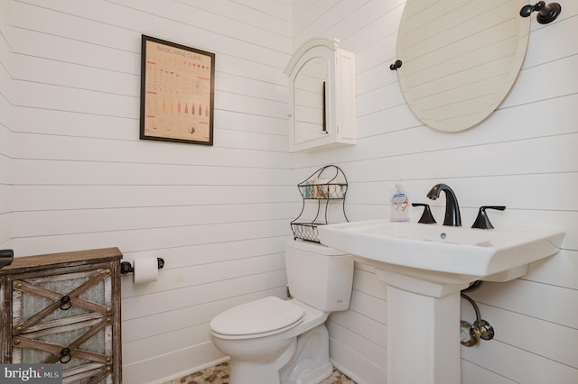 bathroom with toilet and wood walls