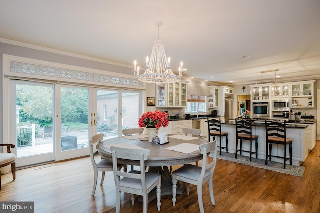 dining room with light hardwood / wood-style floors, an inviting chandelier, and ornamental molding