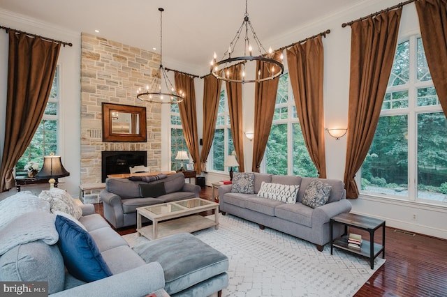 living room with a healthy amount of sunlight, a notable chandelier, wood-type flooring, and a fireplace