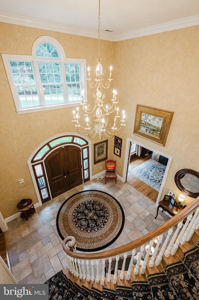 foyer with crown molding, hardwood / wood-style flooring, and a chandelier