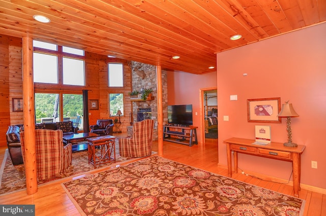 interior space with a stone fireplace, light hardwood / wood-style flooring, and wooden ceiling