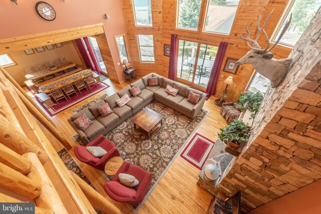 living room featuring wood walls, a towering ceiling, and hardwood / wood-style flooring