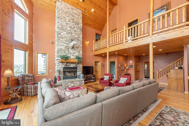 living room featuring high vaulted ceiling, a wealth of natural light, and a stone fireplace