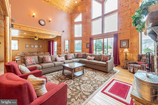 living room featuring wood ceiling, wood walls, light hardwood / wood-style floors, and high vaulted ceiling