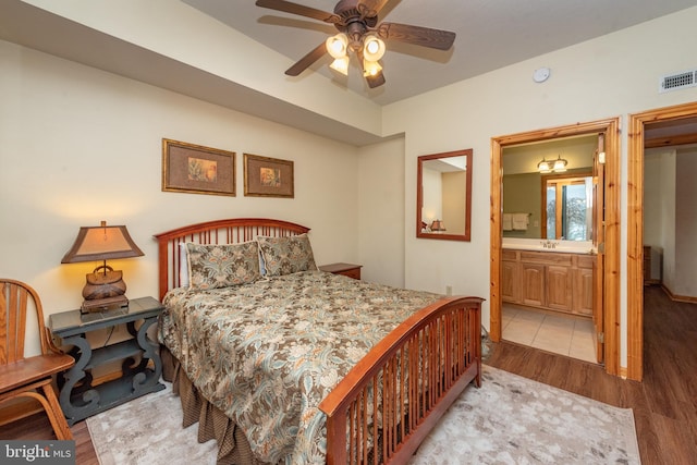 bedroom featuring ceiling fan, light wood-type flooring, connected bathroom, and sink