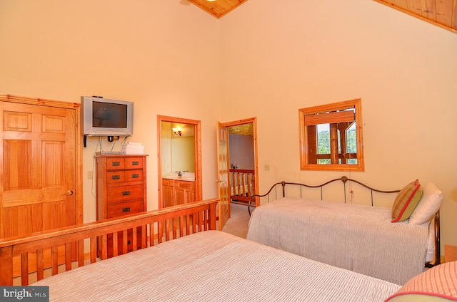 bedroom featuring high vaulted ceiling, ensuite bath, and carpet flooring