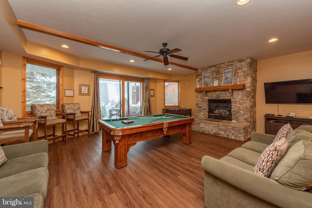 playroom with wood-type flooring, pool table, a textured ceiling, a stone fireplace, and ceiling fan