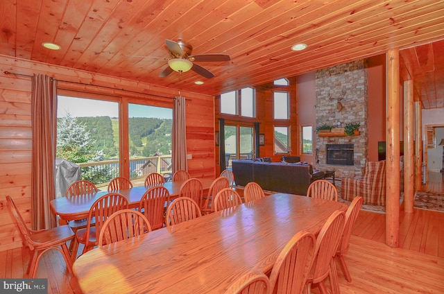 dining room featuring wood ceiling, vaulted ceiling, a fireplace, ceiling fan, and light hardwood / wood-style flooring