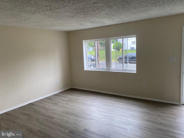 empty room featuring a textured ceiling and dark hardwood / wood-style floors