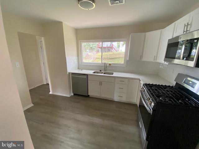 kitchen featuring white cabinets, sink, light wood-type flooring, tasteful backsplash, and stainless steel appliances