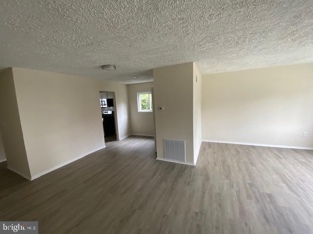 spare room featuring dark hardwood / wood-style floors and a textured ceiling