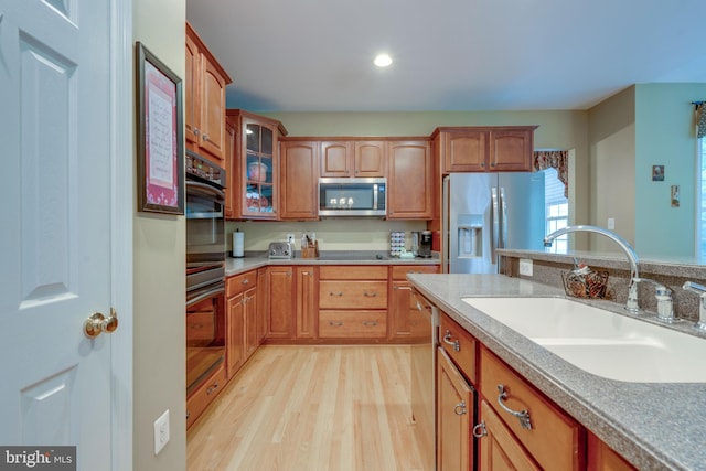 kitchen with appliances with stainless steel finishes, light hardwood / wood-style floors, and sink