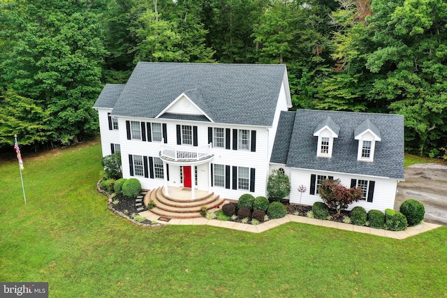 colonial inspired home with a balcony and a front yard