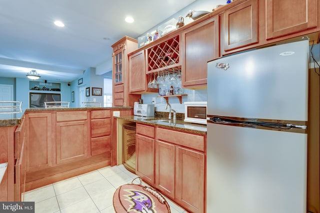 kitchen with stainless steel refrigerator, sink, and light tile patterned floors