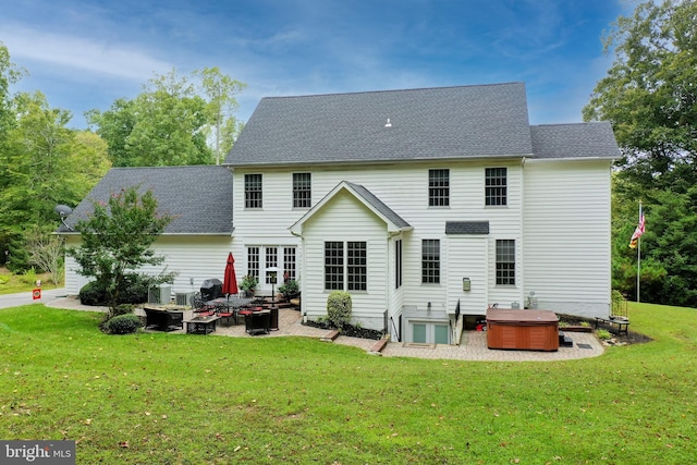 rear view of house featuring a yard, a patio, and a hot tub