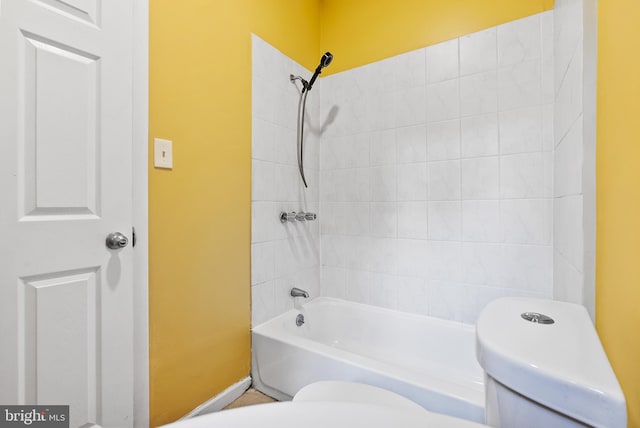 bathroom with tiled shower / bath combo and toilet