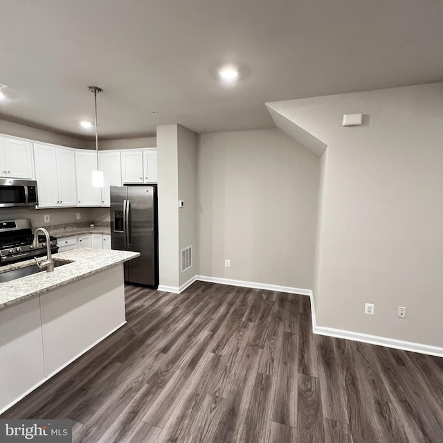 kitchen with white cabinetry, light stone counters, stainless steel appliances, and dark hardwood / wood-style floors