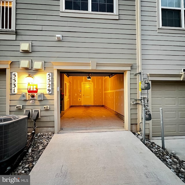 view of exterior entry with cooling unit and a garage