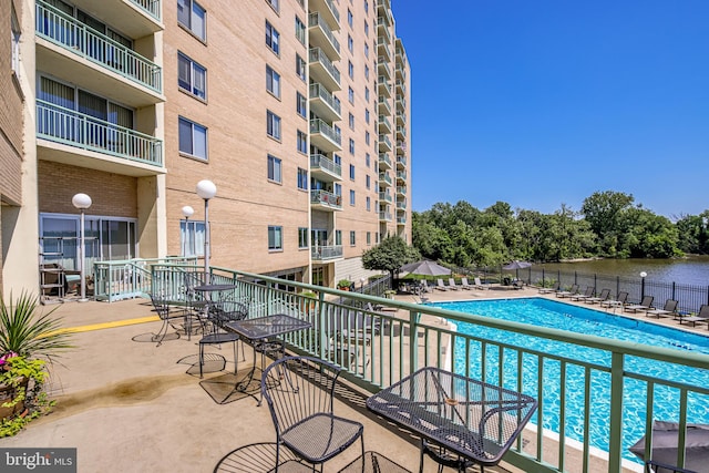 view of pool with a water view and a patio