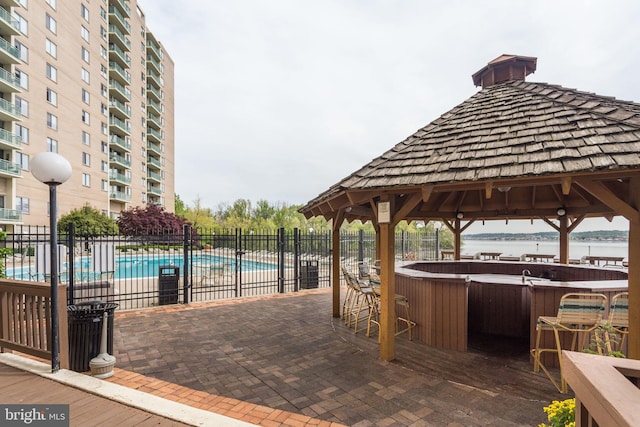 view of patio featuring a gazebo, a pool with hot tub, a water view, and exterior bar