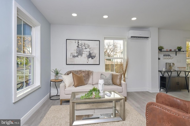 living room with an AC wall unit and light hardwood / wood-style floors