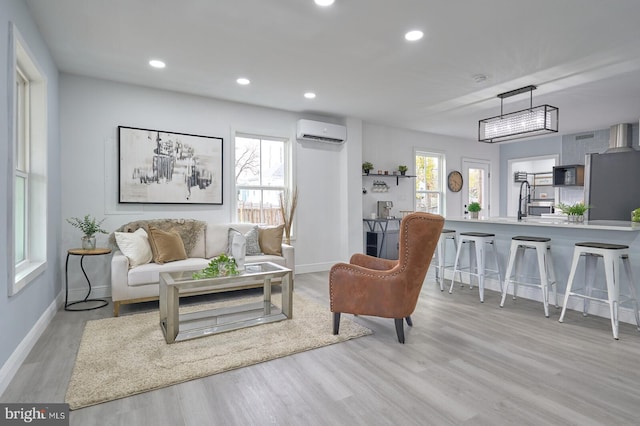 living room with an AC wall unit, a wealth of natural light, and light wood-type flooring