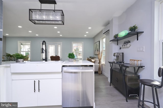 kitchen featuring light wood-type flooring, a wealth of natural light, dishwasher, and white cabinets