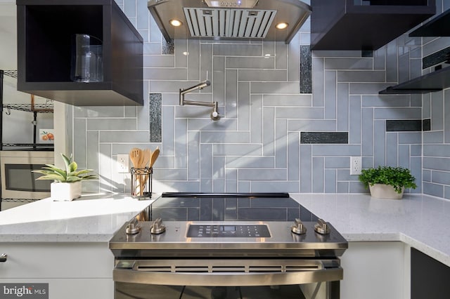 kitchen with white cabinets, backsplash, light stone counters, and stainless steel appliances