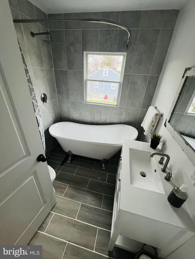 full bathroom featuring independent shower and bath, vanity, tile walls, and toilet