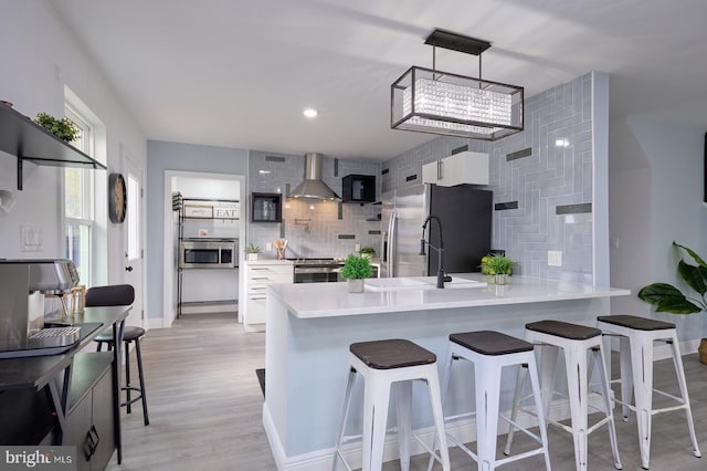 kitchen featuring wall chimney exhaust hood, white cabinets, kitchen peninsula, and stainless steel appliances