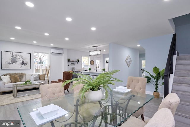 dining room with sink, light hardwood / wood-style flooring, and a wall unit AC