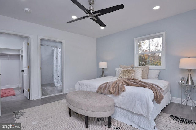 bedroom featuring ceiling fan, ensuite bathroom, wood-type flooring, and a spacious closet