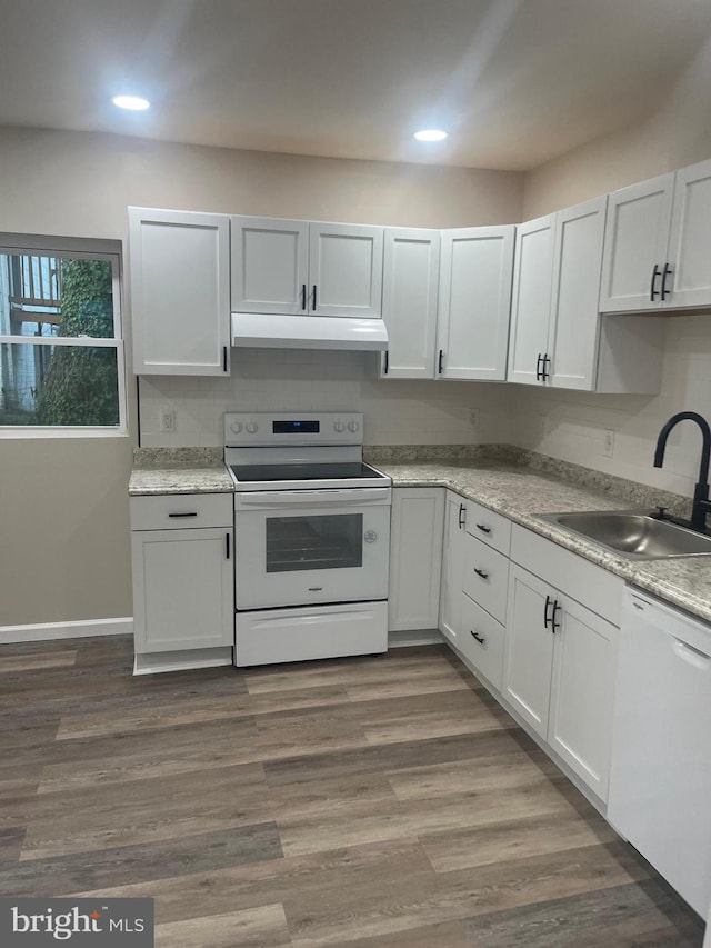 kitchen with white cabinetry, hardwood / wood-style flooring, sink, and white appliances