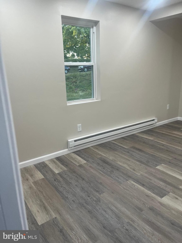 empty room with baseboard heating and dark hardwood / wood-style floors