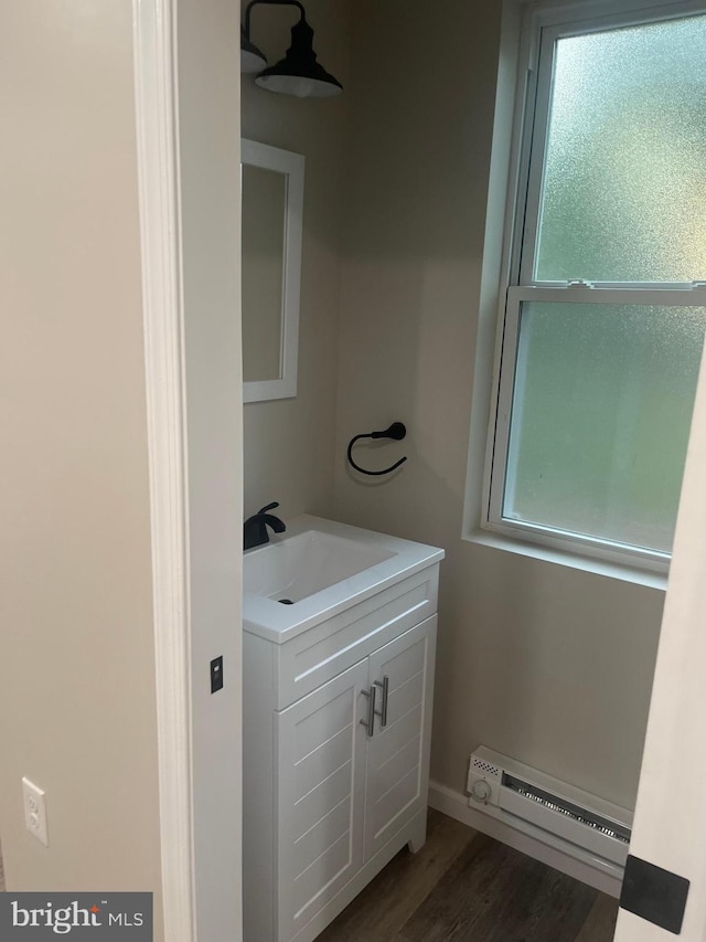 bathroom featuring vanity, hardwood / wood-style floors, and a baseboard radiator