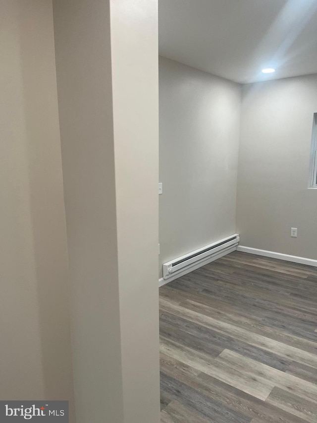 unfurnished room with a baseboard radiator and wood-type flooring