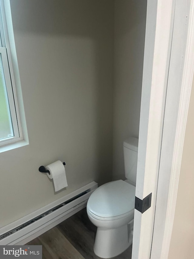 bathroom featuring a baseboard heating unit, hardwood / wood-style flooring, and toilet