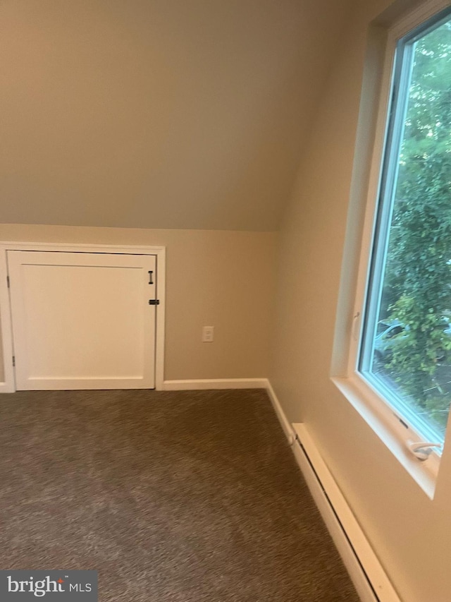 bonus room featuring dark carpet, vaulted ceiling, and a baseboard heating unit