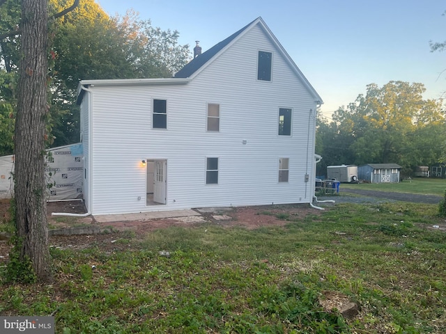 back of property featuring a storage shed and a lawn